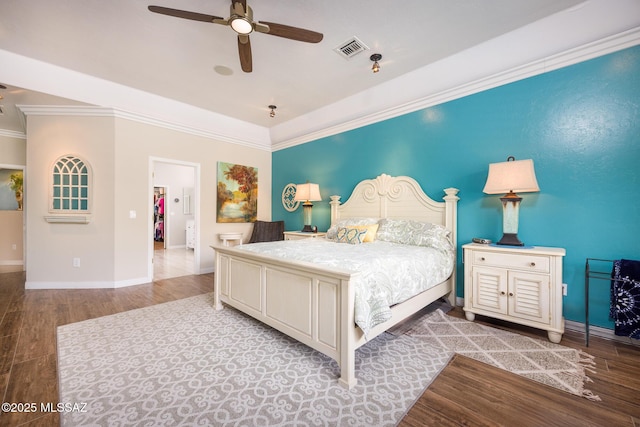 bedroom featuring a ceiling fan, wood finished floors, visible vents, baseboards, and crown molding