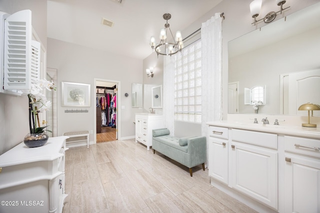 full bathroom with a walk in closet, baseboards, a chandelier, and vanity