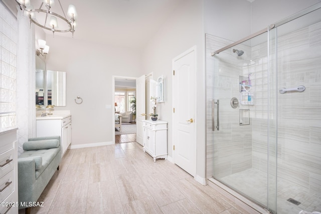 ensuite bathroom featuring connected bathroom, an inviting chandelier, a shower stall, lofted ceiling, and vanity