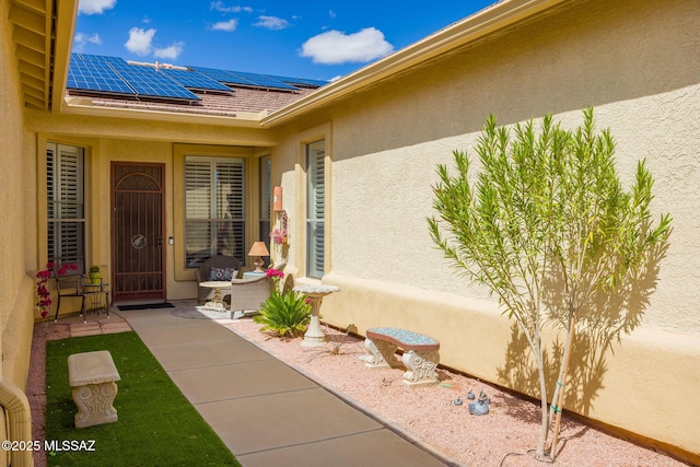 view of exterior entry with stucco siding and roof mounted solar panels