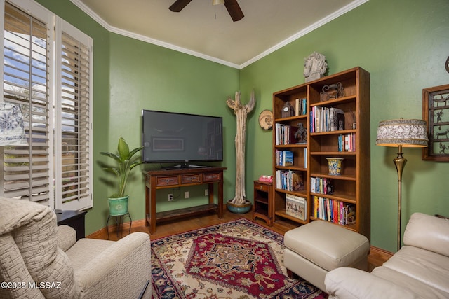 living area with baseboards, wood finished floors, ceiling fan, and ornamental molding