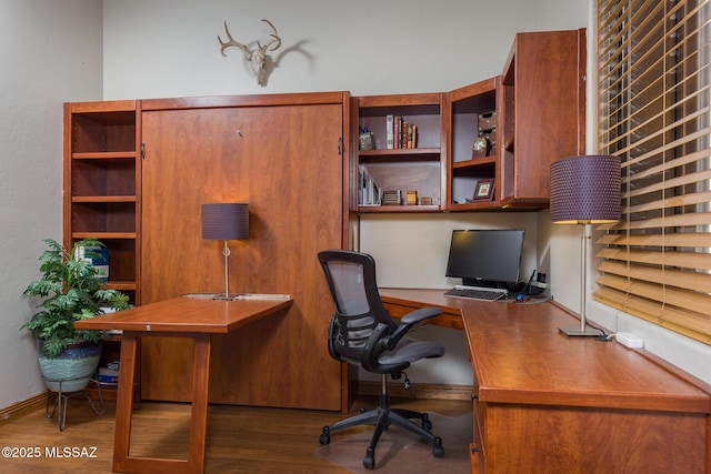 office featuring baseboards, wood finished floors, and built in study area