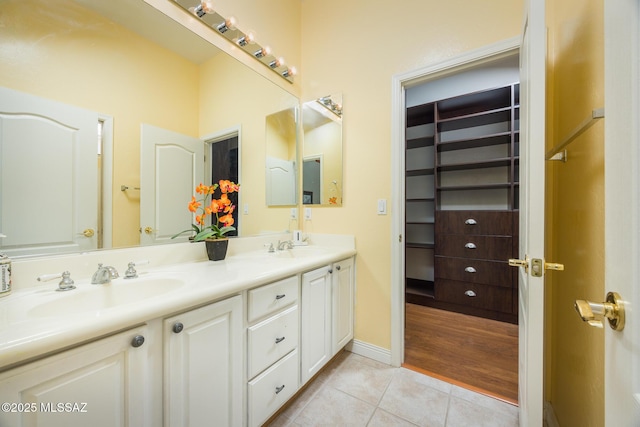 full bath featuring tile patterned floors, double vanity, baseboards, and a sink