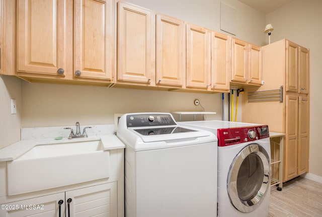 washroom featuring washing machine and clothes dryer, cabinet space, and a sink