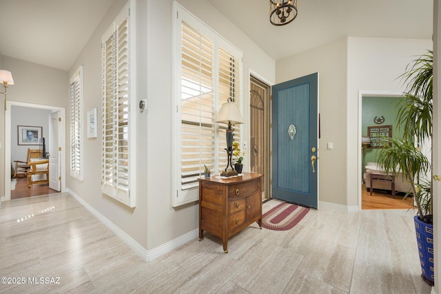 foyer entrance featuring wood finished floors, baseboards, a wealth of natural light, and a chandelier