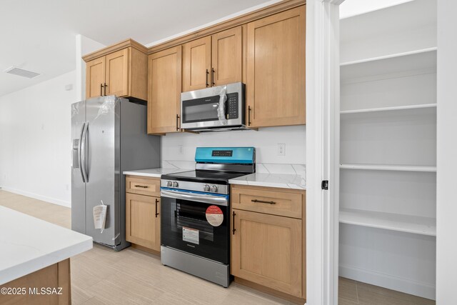 kitchen with visible vents, light floors, stainless steel appliances, and baseboards