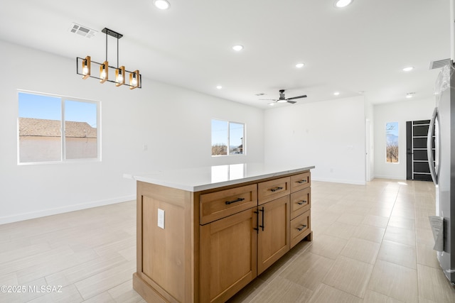 kitchen with baseboards, visible vents, recessed lighting, stainless steel fridge, and a center island