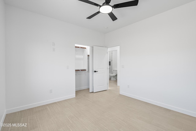 unfurnished bedroom featuring a spacious closet, light wood finished floors, baseboards, a closet, and a ceiling fan