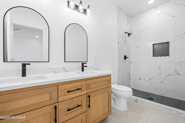 full bathroom with a sink, toilet, double vanity, and a tile shower