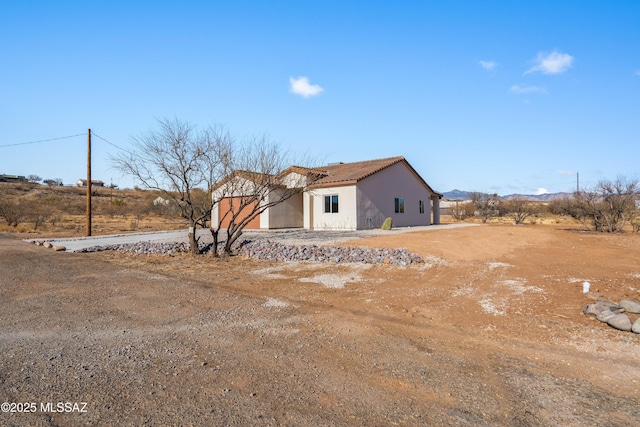 rear view of property with stucco siding and a tile roof