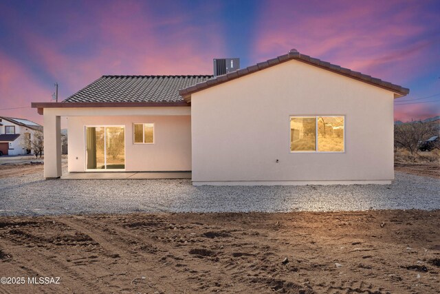 rear view of house featuring a tile roof, central AC unit, and stucco siding