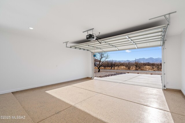 garage with a garage door opener, a mountain view, and baseboards