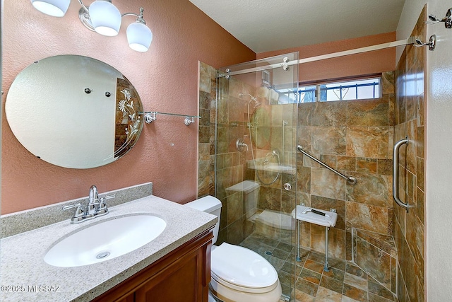 bathroom with vanity, a textured wall, a stall shower, and toilet