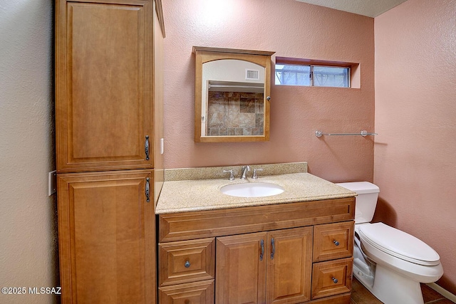 half bathroom with toilet, a textured wall, visible vents, and vanity