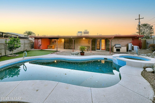 pool at dusk with fence, a patio, a pool with connected hot tub, and grilling area