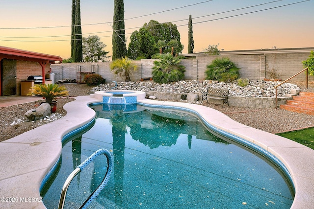 pool at dusk featuring a patio, a fenced backyard, and a pool with connected hot tub