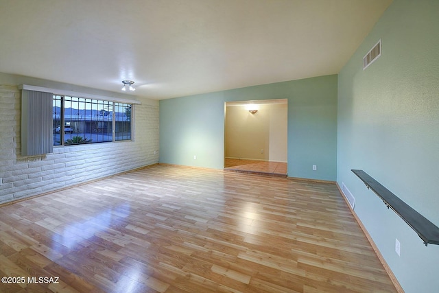 empty room with visible vents, baseboards, and wood finished floors