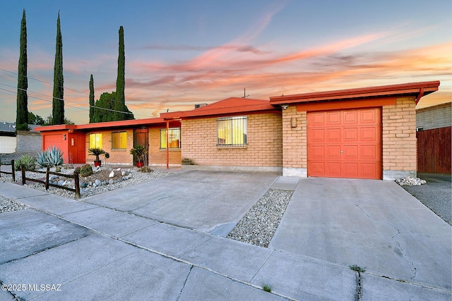 view of front of house featuring brick siding, driveway, and a garage