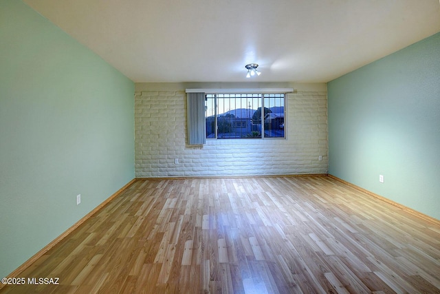 spare room featuring baseboards and wood finished floors