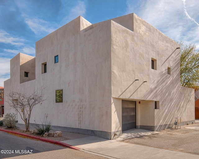 view of side of property with an attached garage, driveway, and stucco siding