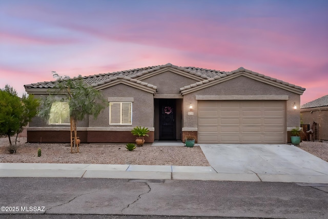 view of front of house featuring stucco siding, concrete driveway, an attached garage, and a tile roof