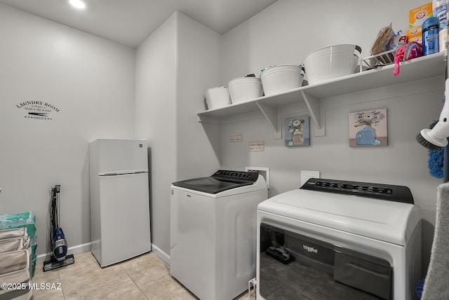 laundry area with light tile patterned floors, baseboards, independent washer and dryer, and laundry area