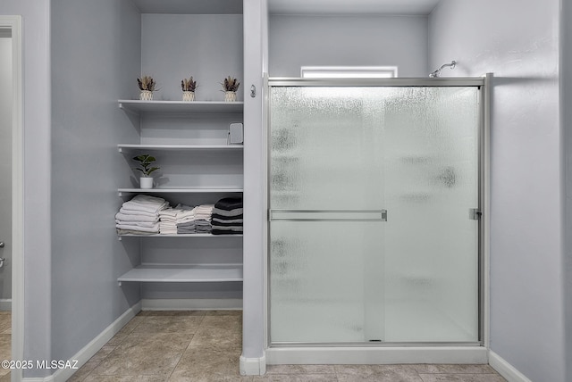 full bath featuring a stall shower and baseboards