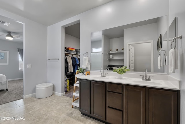 full bathroom with a sink, a walk in closet, visible vents, and double vanity