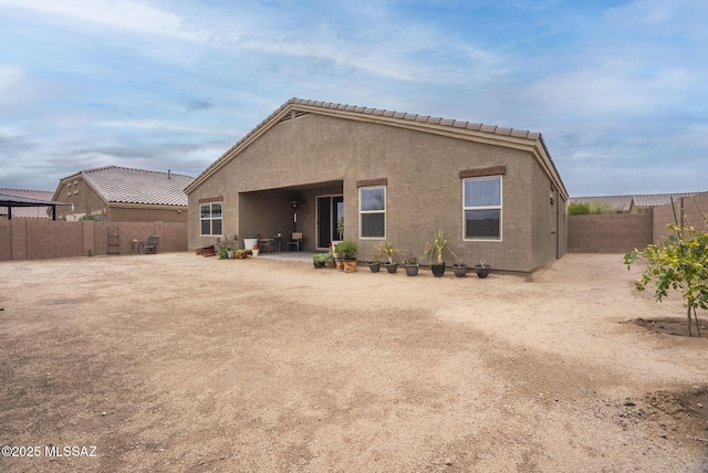 rear view of property with stucco siding, a patio, a fenced backyard, and a tiled roof