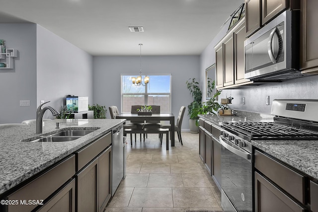 kitchen with a sink, light stone countertops, visible vents, and stainless steel appliances