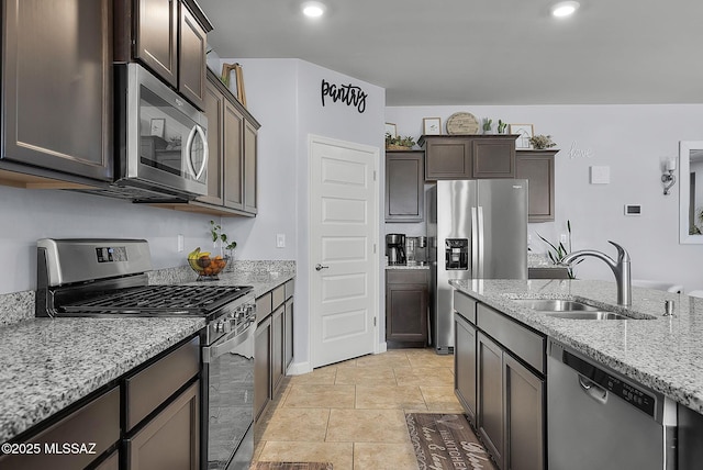 kitchen with light stone countertops, dark brown cabinetry, recessed lighting, stainless steel appliances, and a sink