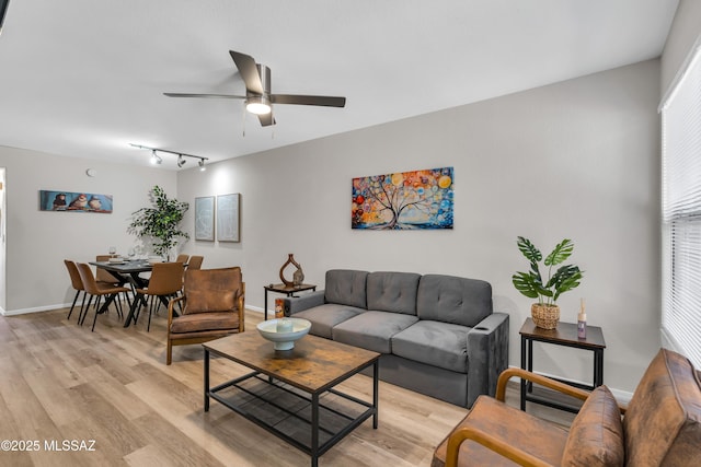 living area with baseboards, light wood-type flooring, and ceiling fan