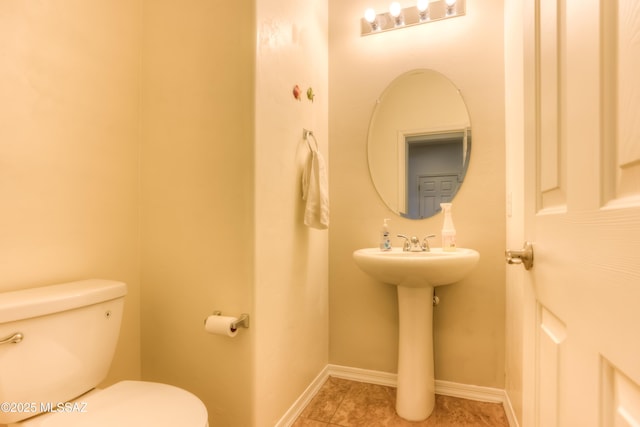 half bathroom featuring tile patterned floors, baseboards, and toilet