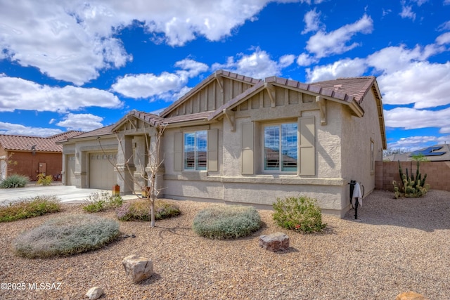 view of front of property featuring fence, a garage, driveway, and stucco siding