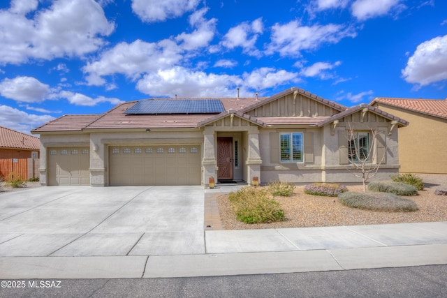 view of front facade featuring solar panels, a tiled roof, stucco siding, driveway, and an attached garage