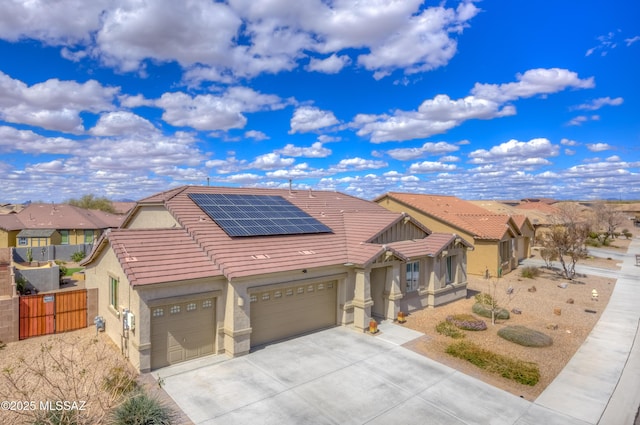 view of front of property featuring driveway, stucco siding, a garage, a tile roof, and roof mounted solar panels