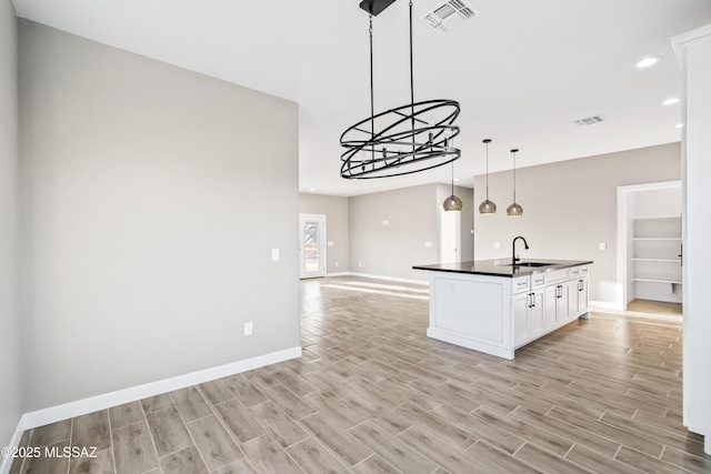 kitchen featuring a sink, visible vents, light wood-type flooring, and dark countertops