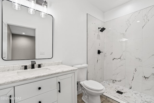 bathroom featuring a marble finish shower, toilet, and vanity