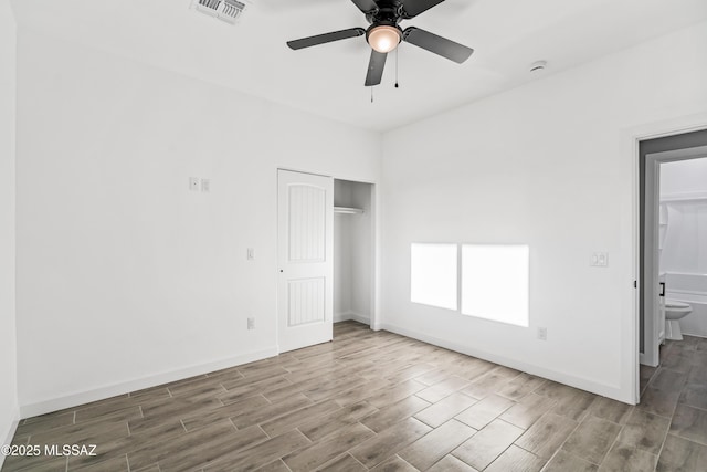 unfurnished bedroom featuring visible vents, baseboards, a closet, and wood tiled floor