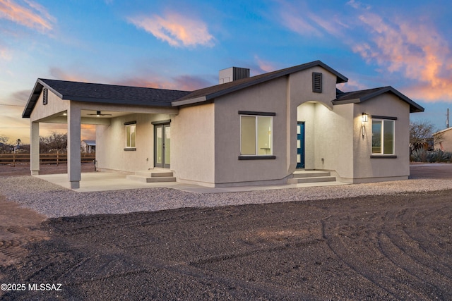 back of property at dusk with stucco siding and a patio area