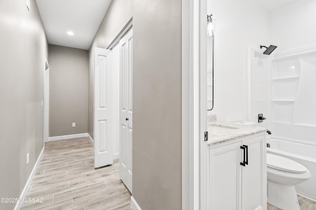 corridor featuring a sink, baseboards, recessed lighting, and light wood finished floors