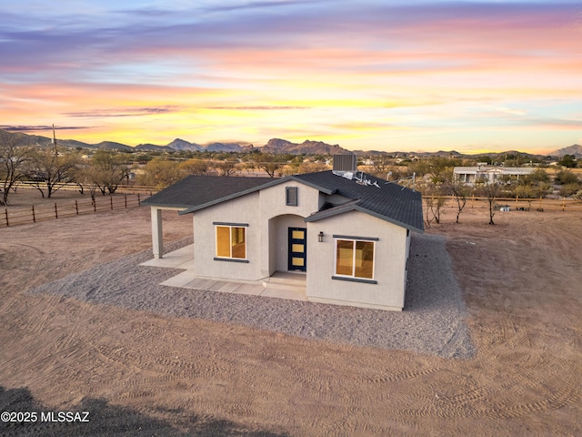 view of front of house featuring fence, a mountain view, and stucco siding