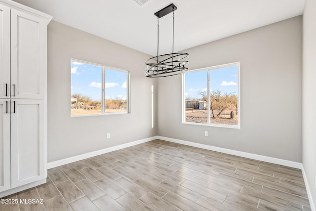 unfurnished dining area featuring plenty of natural light, light wood-type flooring, and baseboards