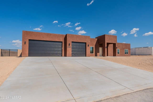 southwest-style home with stucco siding, concrete driveway, an attached garage, and fence