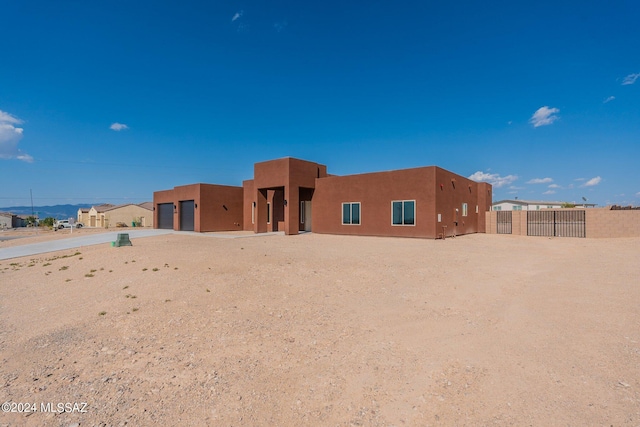 back of house featuring stucco siding, driveway, a garage, and fence