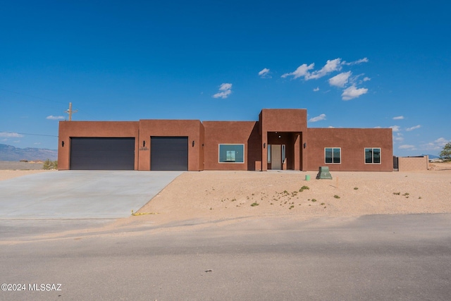 pueblo revival-style home featuring a garage, driveway, and stucco siding