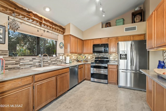 kitchen featuring brown cabinetry, visible vents, lofted ceiling, a sink, and stainless steel appliances