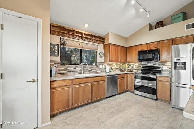 kitchen with light countertops, vaulted ceiling, appliances with stainless steel finishes, and a sink