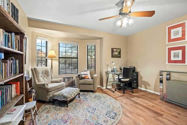 sitting room with baseboards, wood finished floors, and a ceiling fan