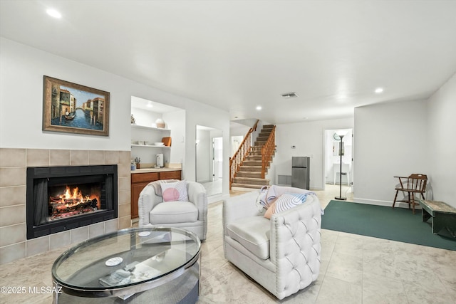 living area featuring stairs, visible vents, recessed lighting, and a tiled fireplace